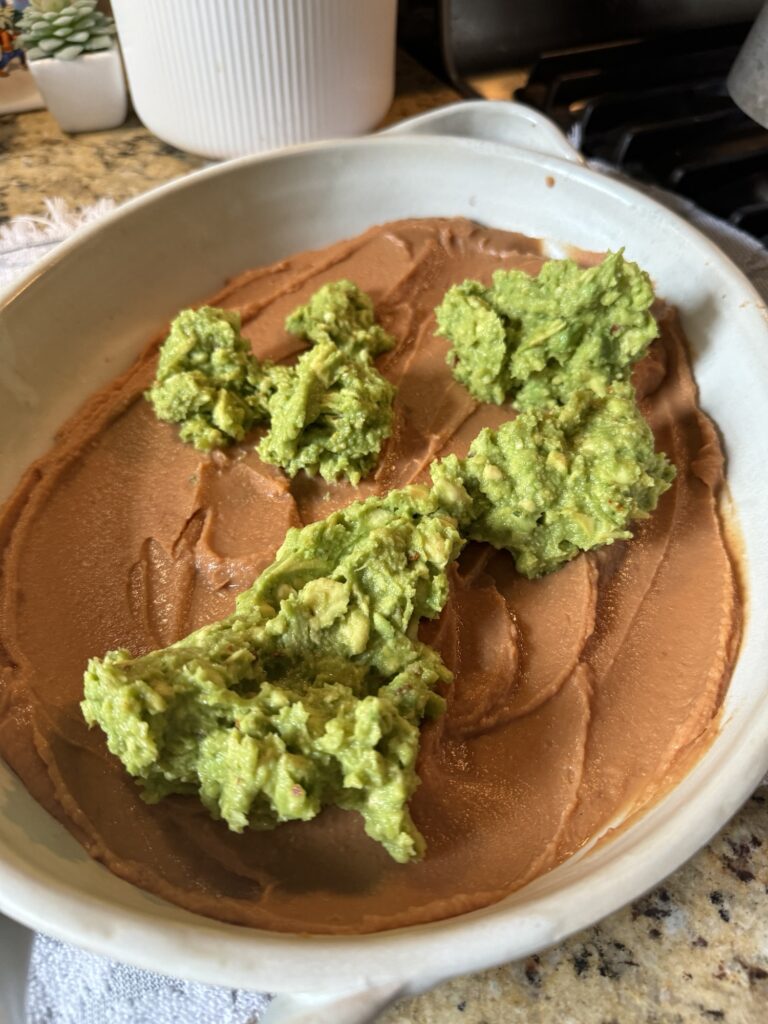 Globs of avocado on top of the bean dip spread