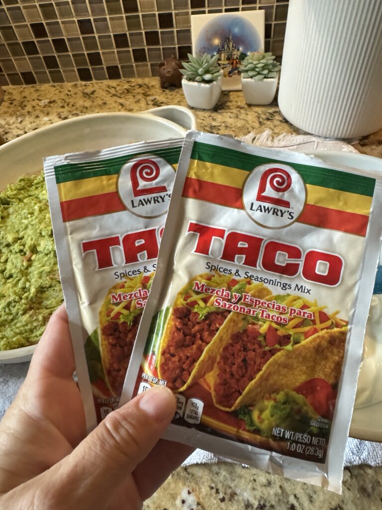 Two Lawry Taco spice seasoning packets held by me