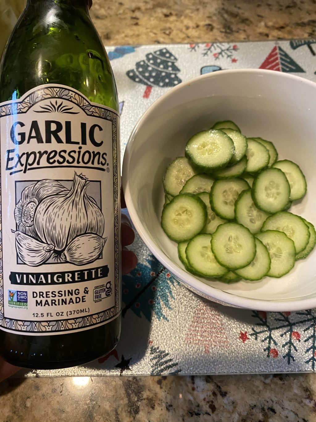 A bottle of Garlic Expressions vinaigrette next to a bowl of sliced cucumbers