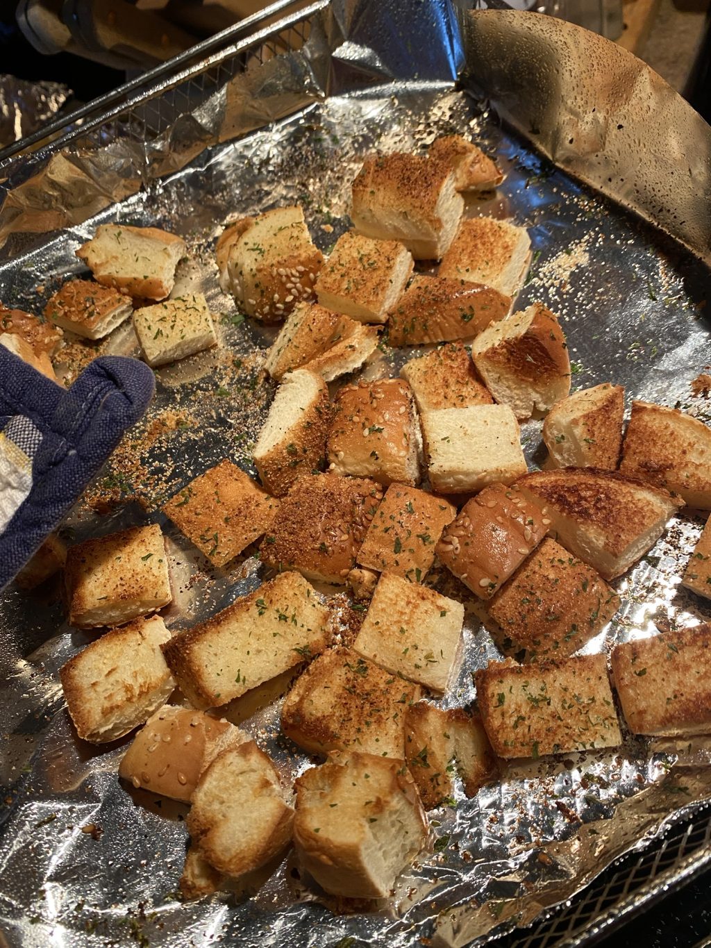 Cubed, toasted hamburger bun pieces on a foil baking sheet