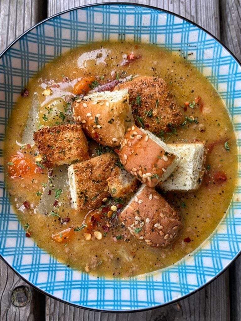 Bowl with creamy beef soup with hamburger bun croutons on top.