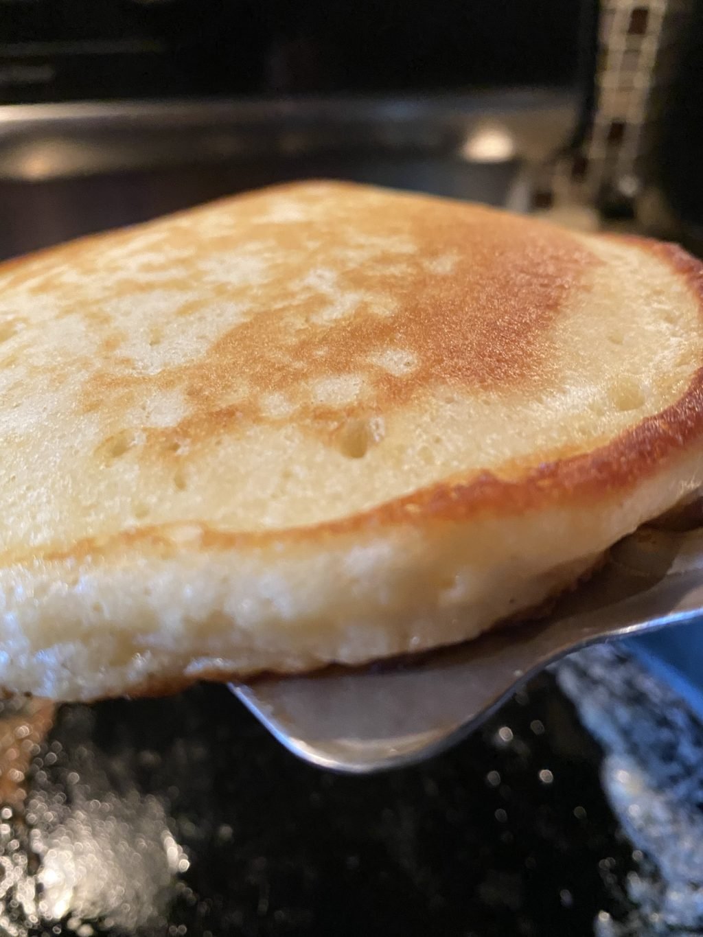 A close up of a pancake being flipped with a spatula