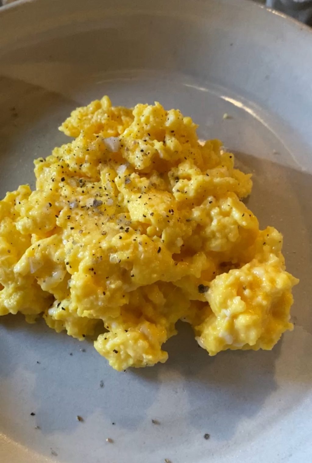 Perfectly cooked scrambled eggs on a plate seasoned with salt and pepper