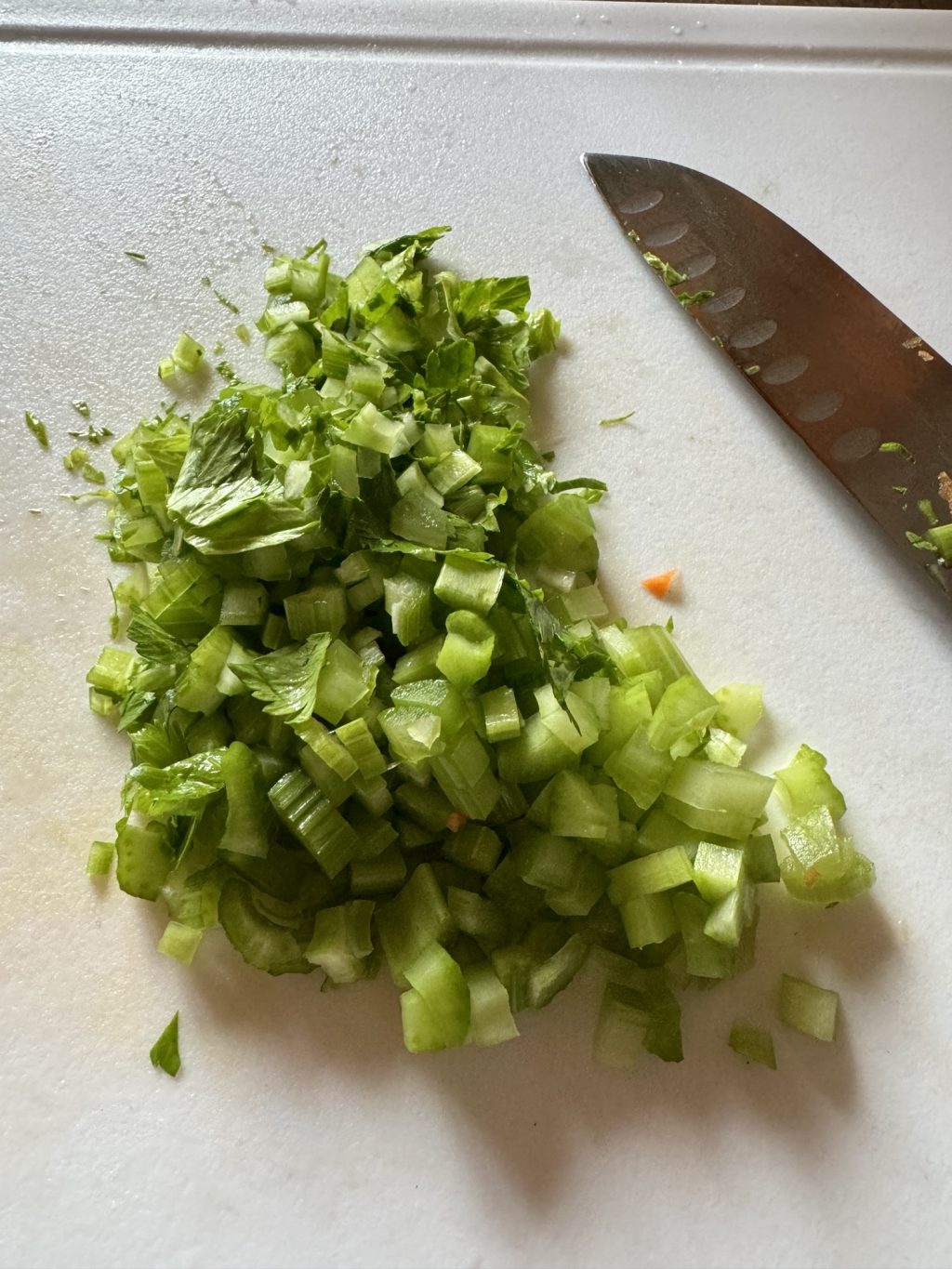 Chopped celery on a cutting board next to a knife