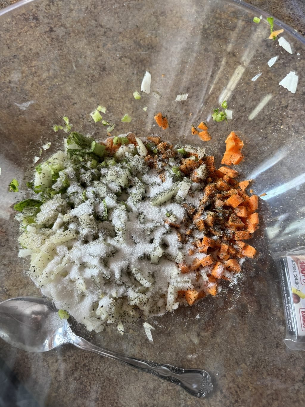 Chopped vegetables in a big glass bowl sprinkled with sugar
