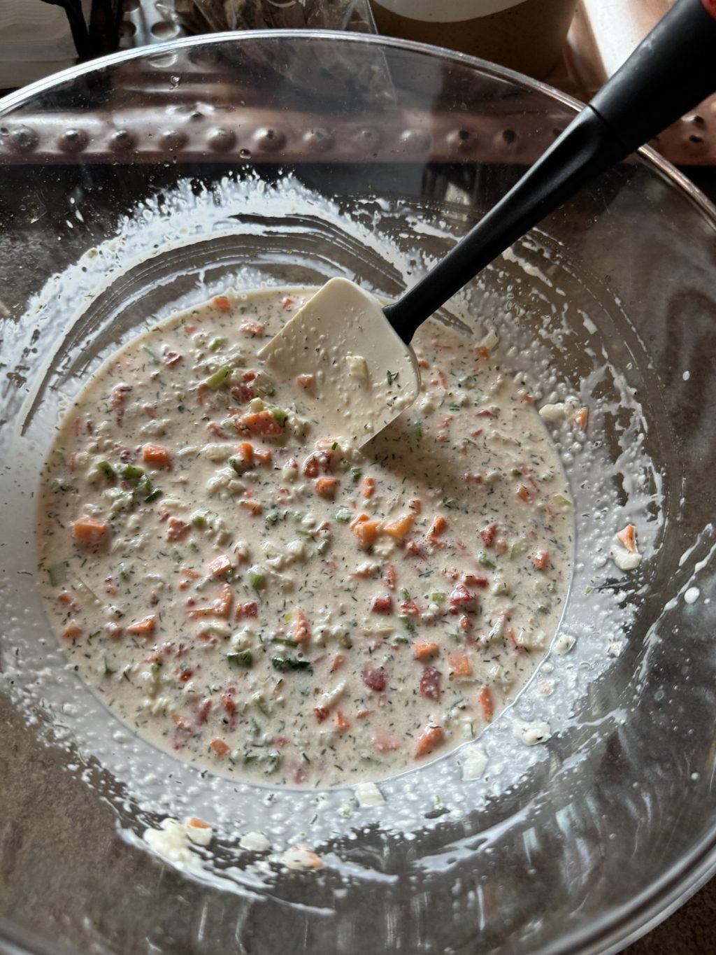 The veggie, vinegar and mayo mixture in a bowl with a spatula in it