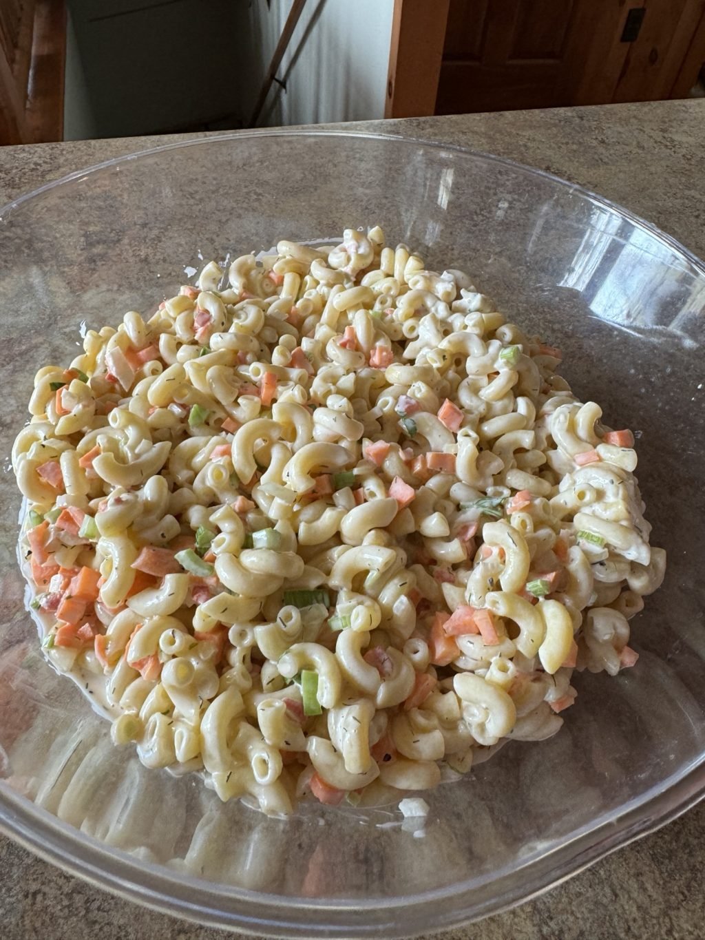 The pasta salad in a glass bowl before the last of the mayo is added