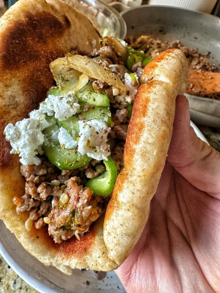 A pita filled with ground meat, onions, and peppers topped with feta cheese