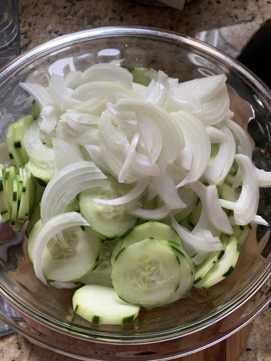 Sliced cucumbers topped with sliced white onion in a bowl