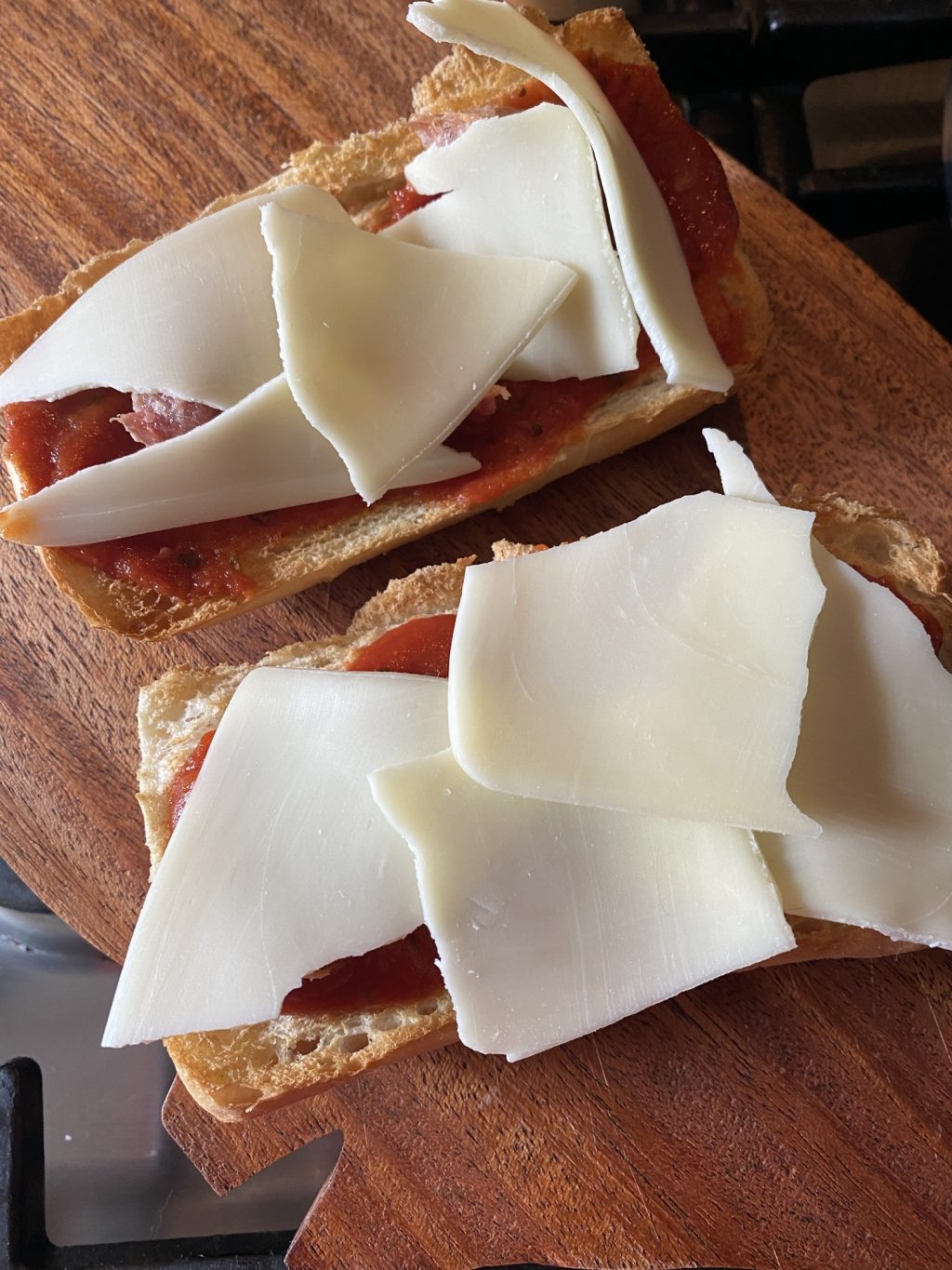 Slices of mozzarella cheese placed over the sausage and pizza sauce spread over toasted bread