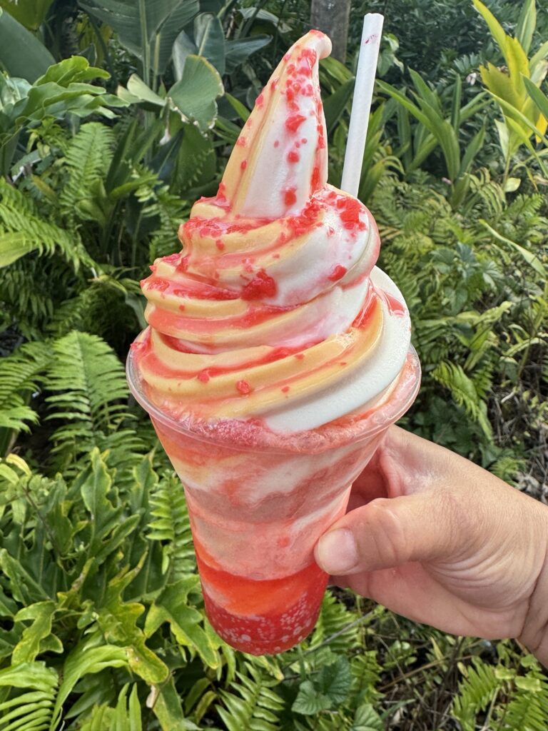 An yellow and white soft serve ice cream swirl float in a red fizzy liquid