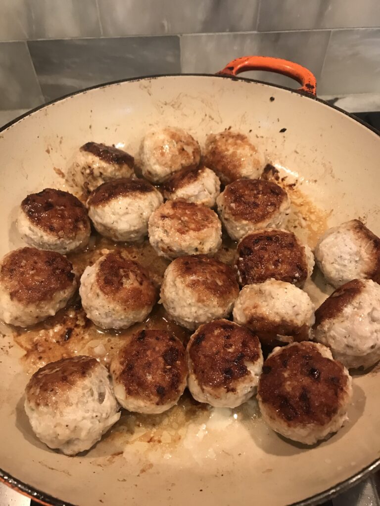 Meatballs pan frying in a skillet