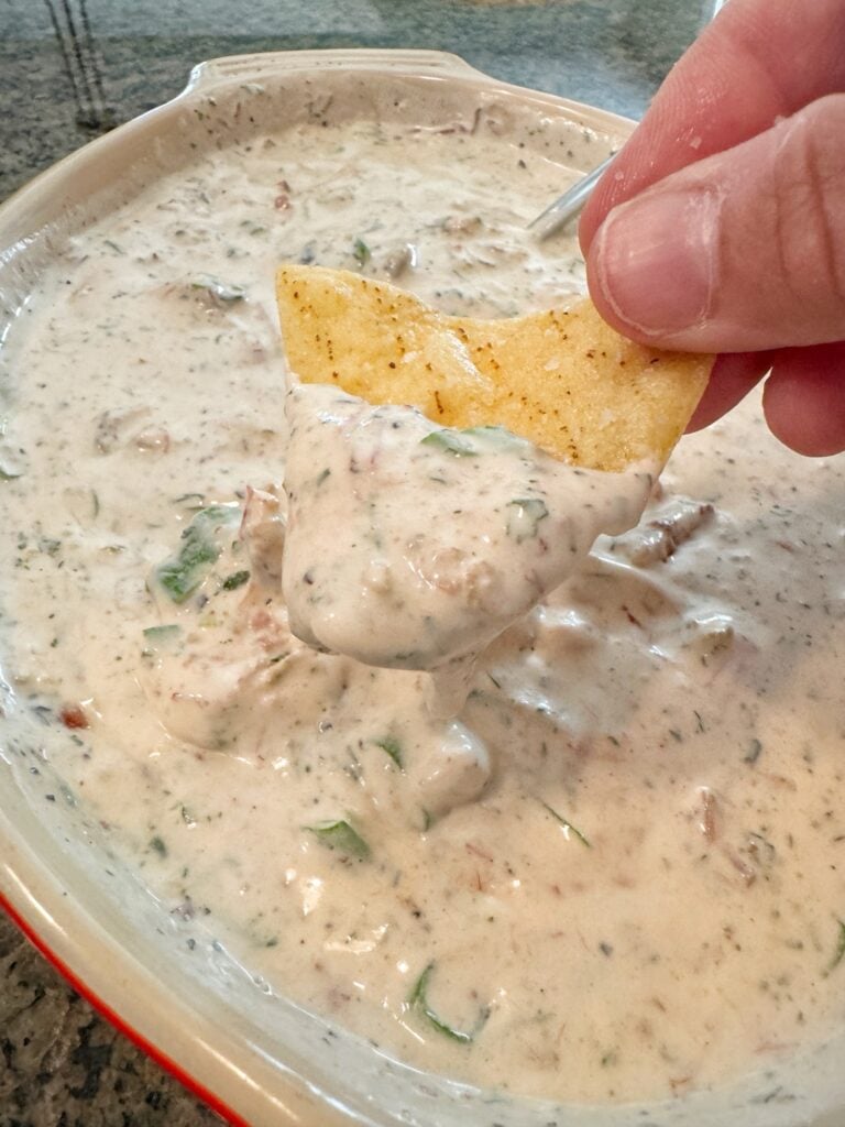 A corn chip being dipped into a white dip