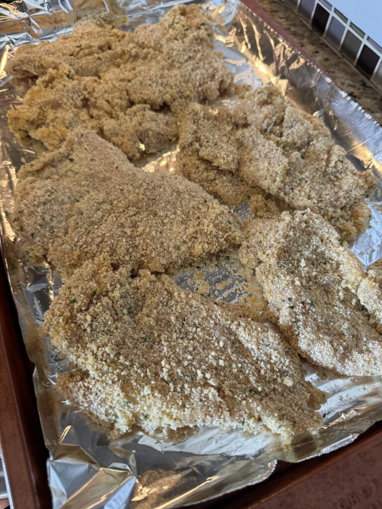Raw, breaded chicken cutlets on a baking sheet