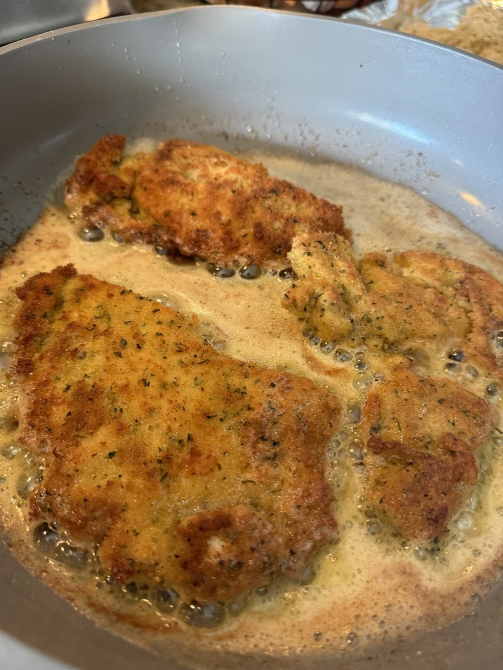 Breaded chicken cutlets pan frying in a butter and oil mixture