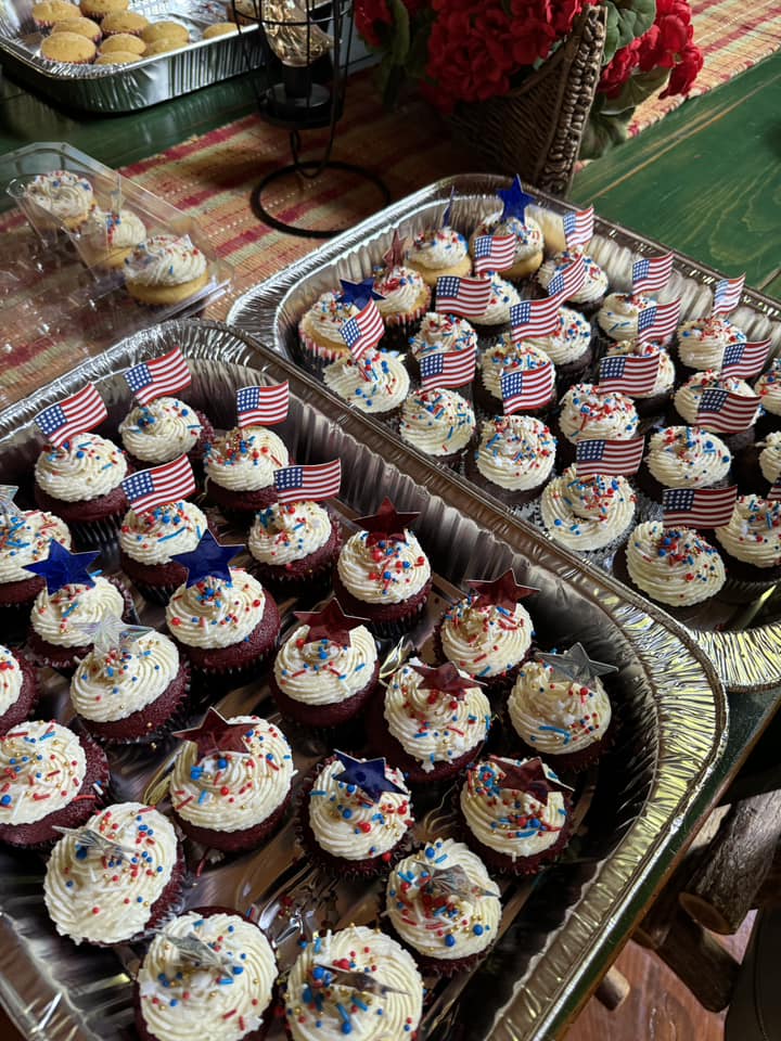Two trays of cupcakes with patriotic decorations.