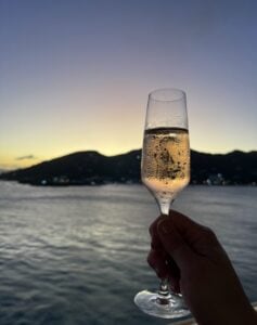 A champagne flute held over water at sunset