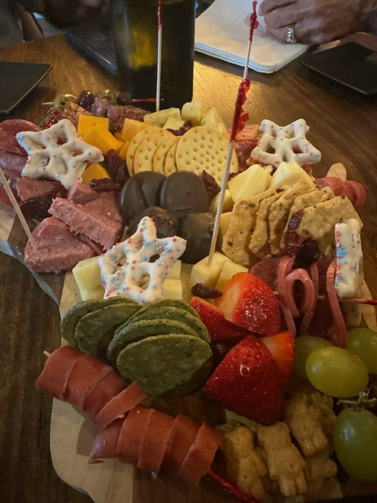 A charcuterie plate with meats, fruits, cookies, and cheese