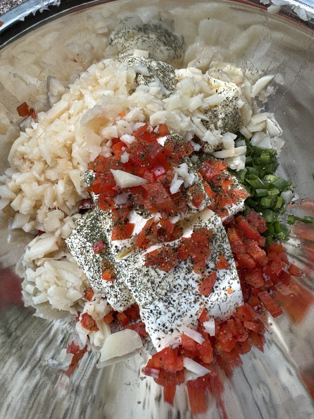 Cream cheese and shredded peppers and onions in a mixing bowl