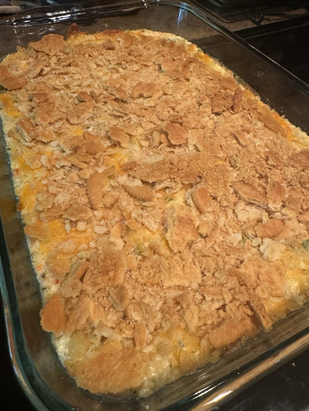 A layer of Ritz crackers crumbled over the party dip in a glass baking dish