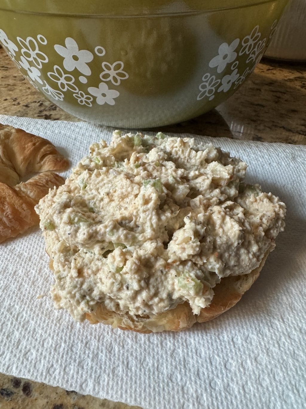 Chicken salad spread on a half of sliced croissant
