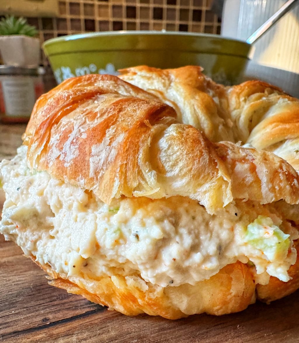 A close up of a croissant sandwich with chicken salad between the halves