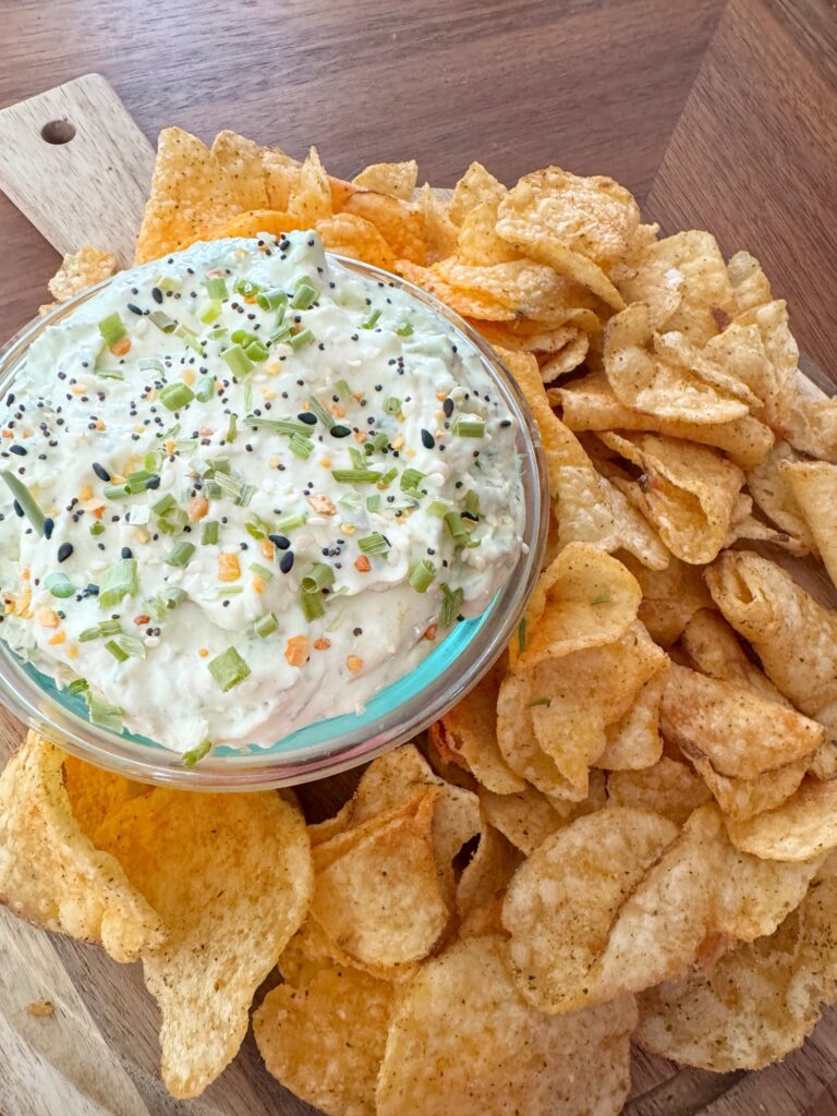 A glass container of smoked salmon dip surrounded by BBQ chips
