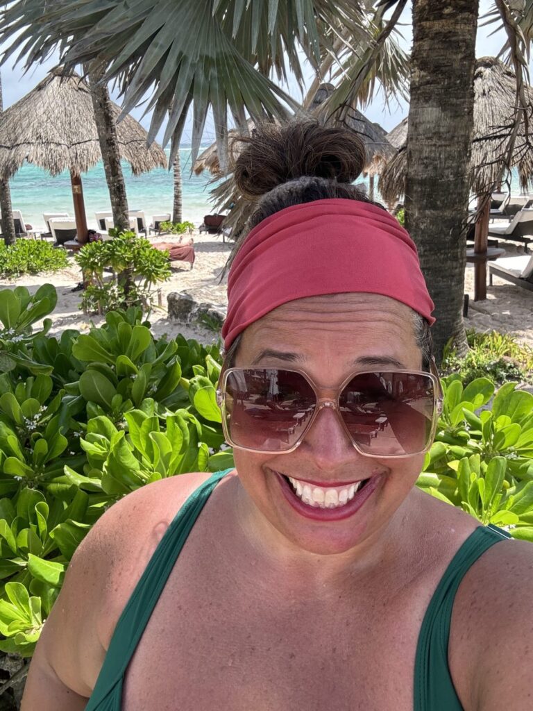 A selfie I took on the beach in front of beach umbrellas and palm trees.