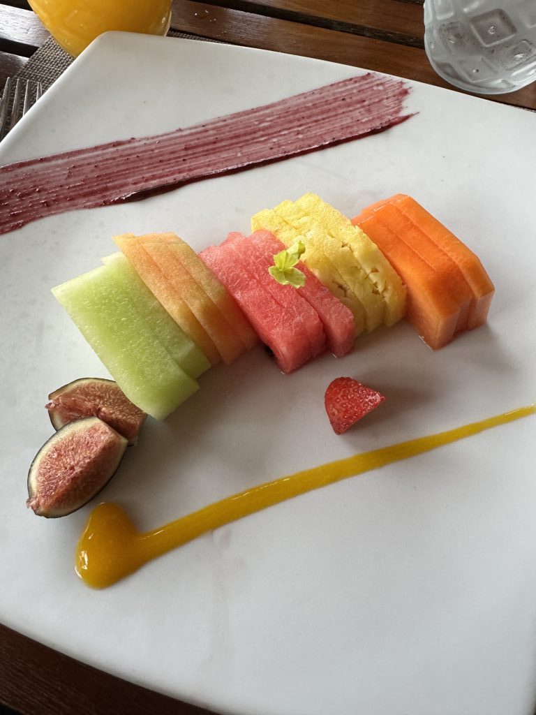 Fruit slices on a white plate with streaks of red and yellow syrup for additional color.