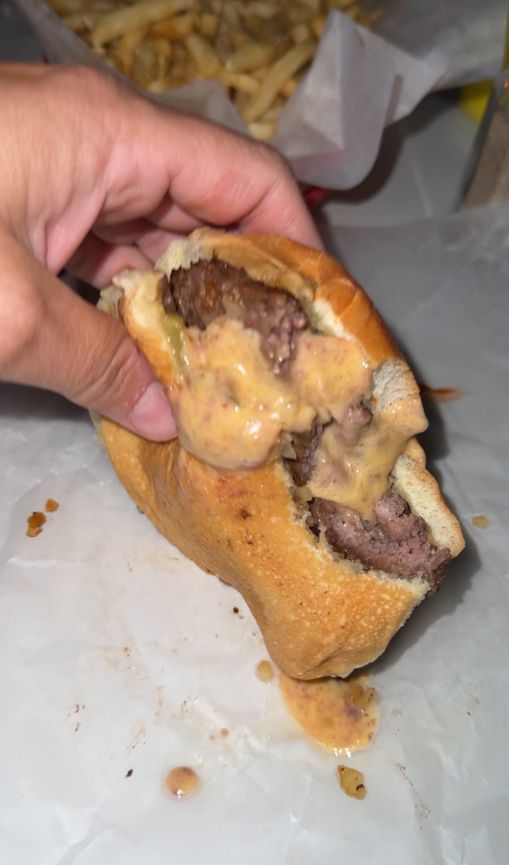 A Juicy Lucy burger with cheese oozing out of the middle.