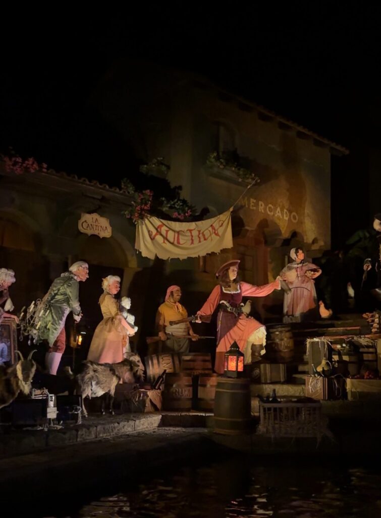 A scene from the Pirates of the Caribbean ride at Disney World showing pirate animatronics under a banner that reads "auction."