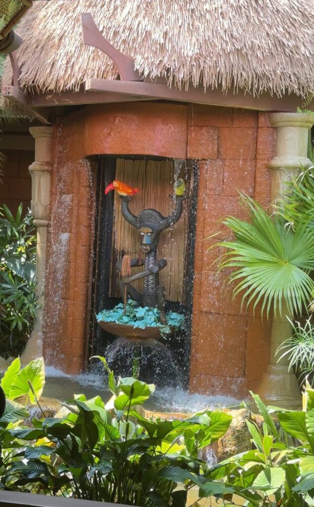 A tiki statue with two animatronic birds outside of the Disney Tiki Room.