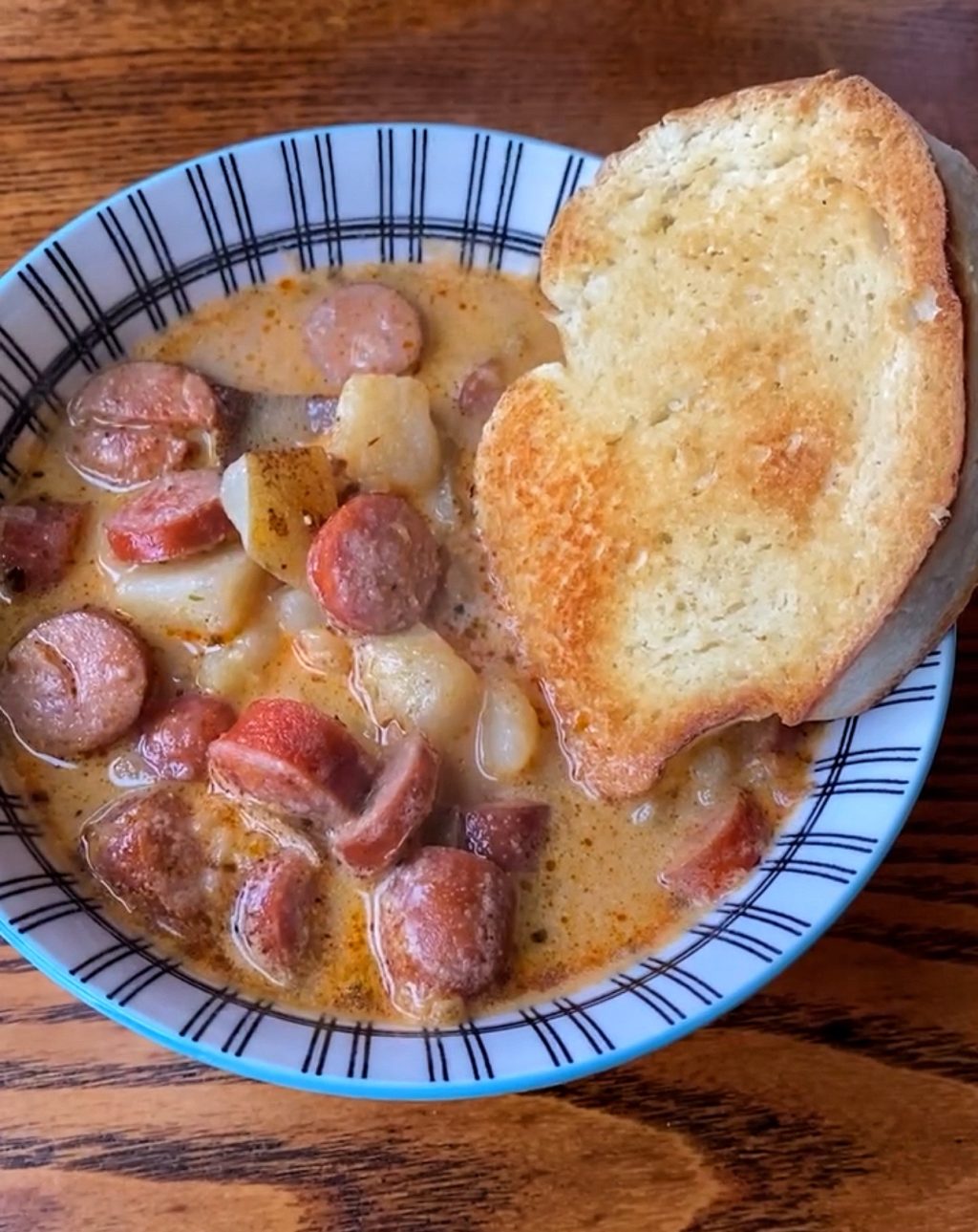 The finished bowl of frankfurter and potato soup with a crust of bread.