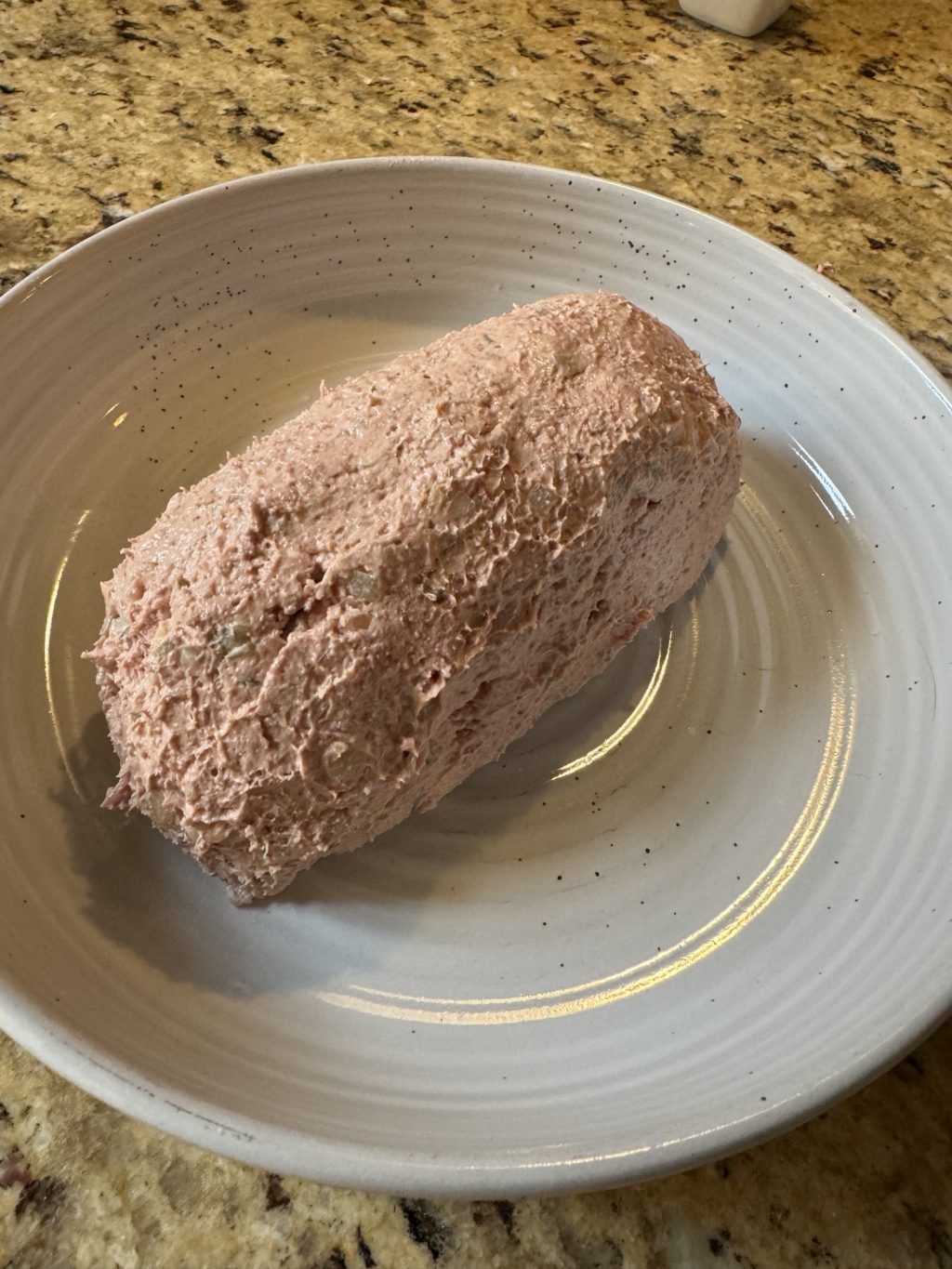 The liver sausage dip, molded into a loaf shape, on a white plate.