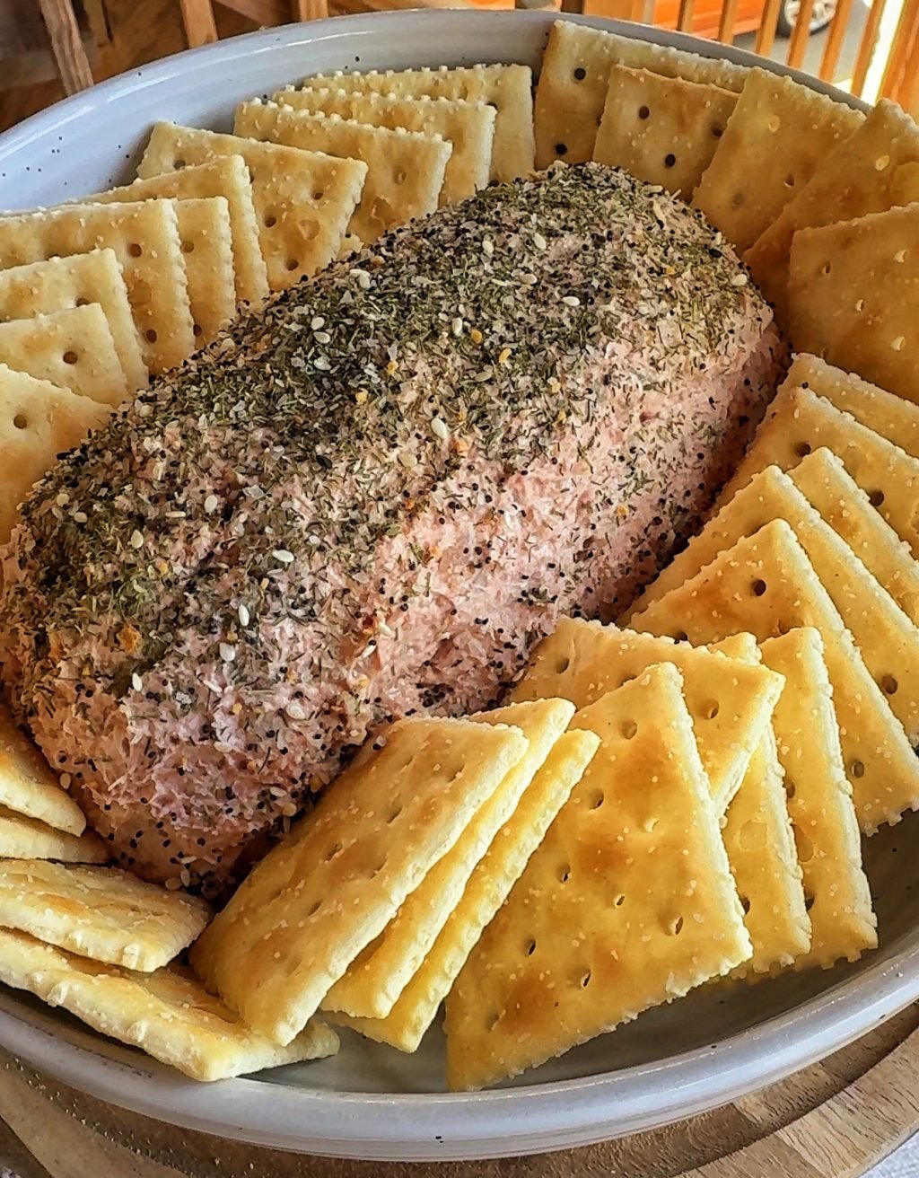 A loaf of liver sausage spread surrounded by Saltine crackers.
