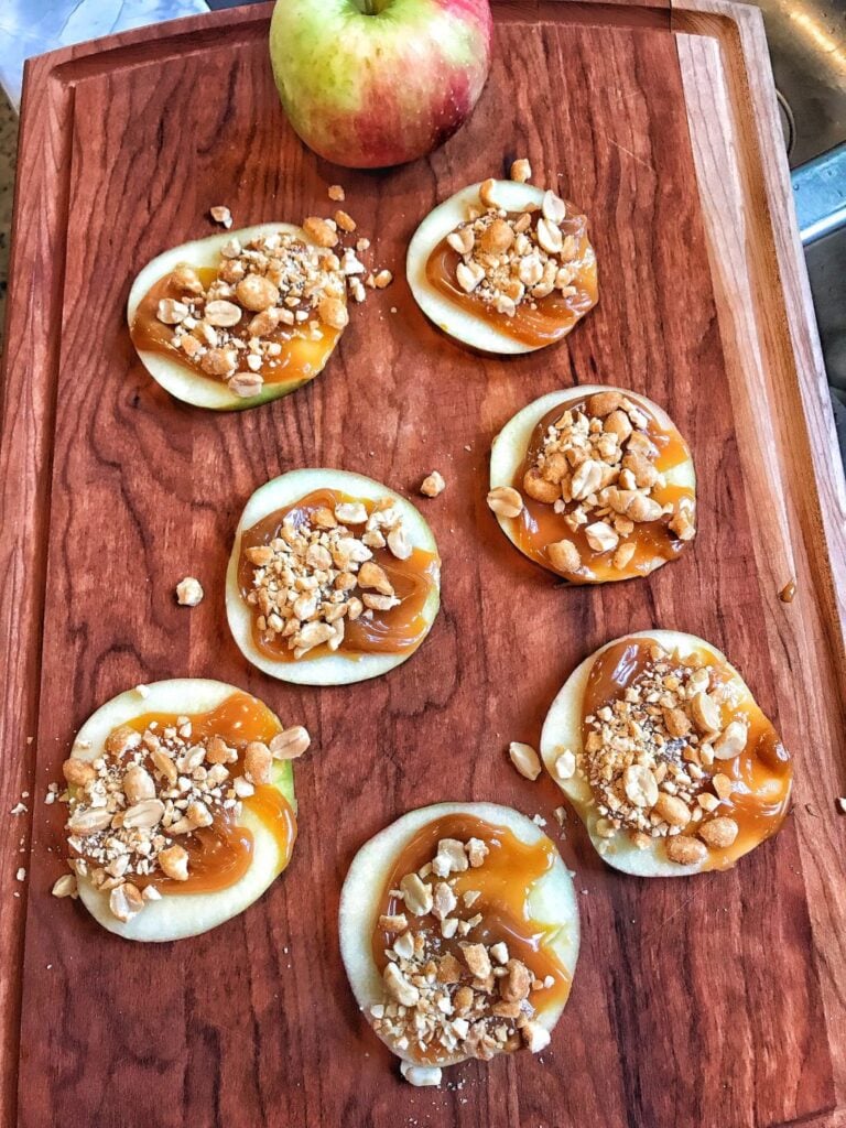 Caramel Apple Slices on a brown cutting board with an apple.