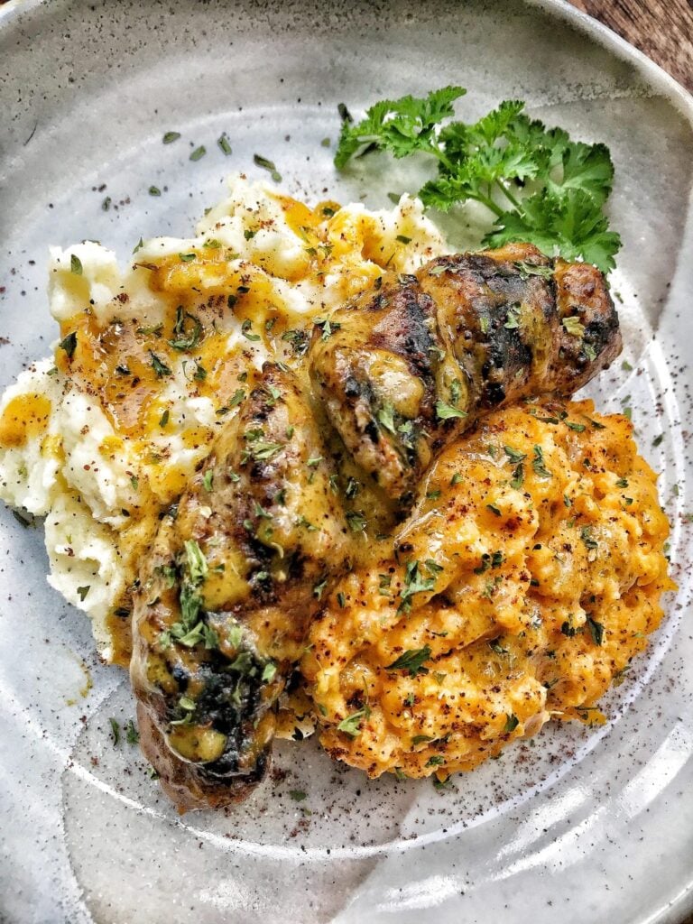 Hasselback Brats with mustard over mashed potatoes.