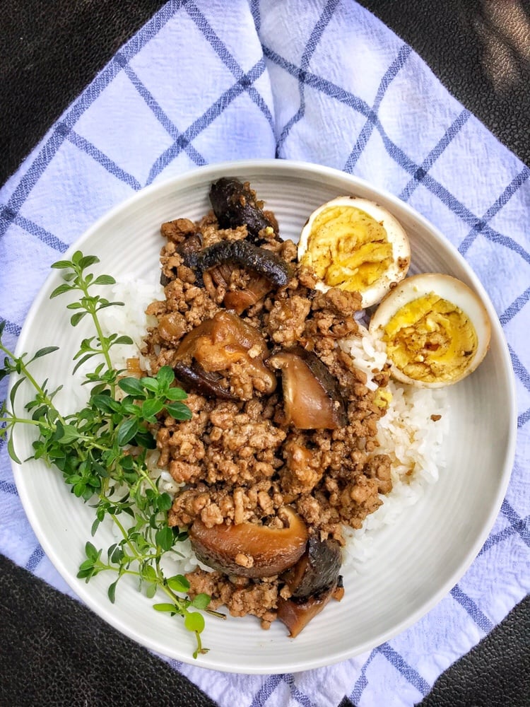 Taiwanese ground Pork and rice on a plate with a hard boiled egg and greens.