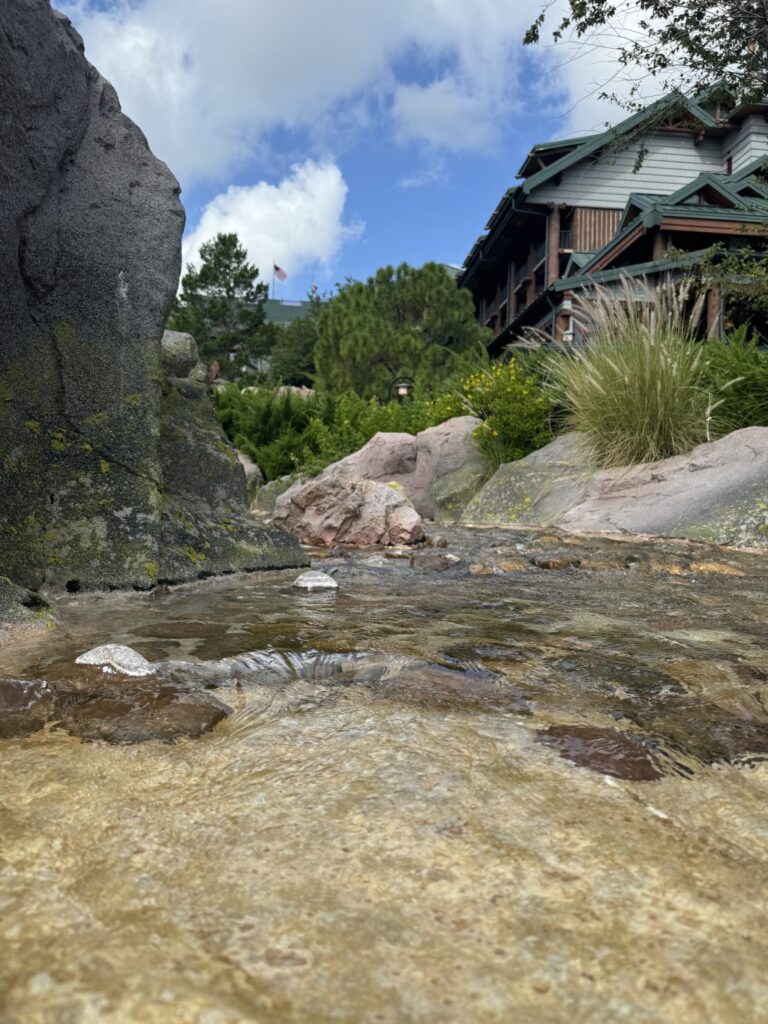 A river, stones, and plants next to part of Disney's Wilderness Lodge.