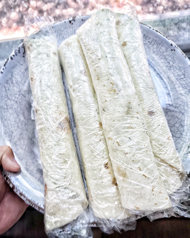 Rolled tortillas wrapped up in plastic wrap.