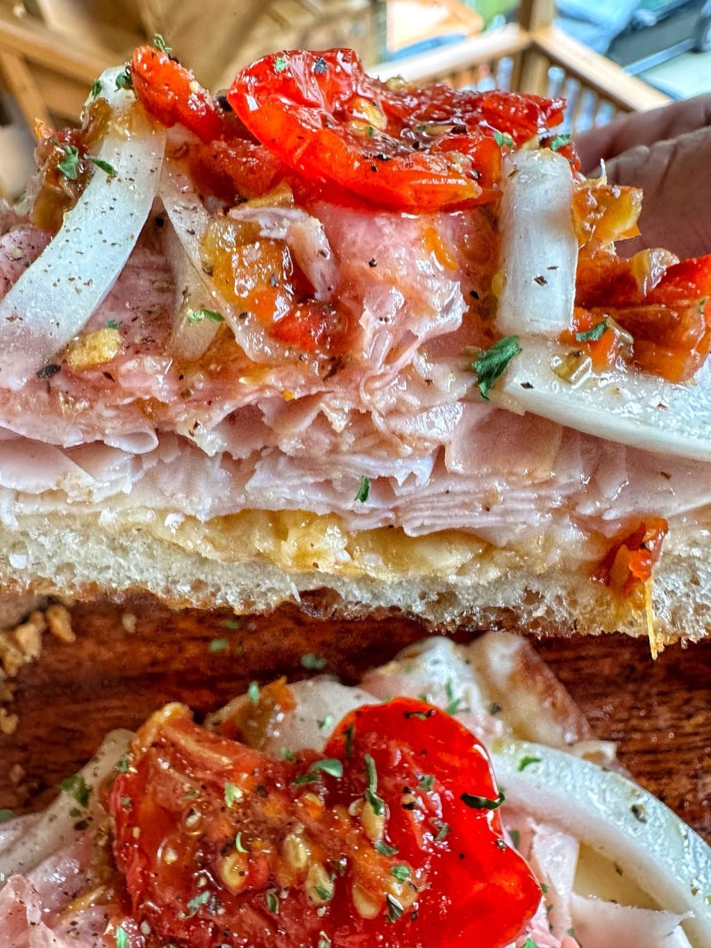 A close up shot of an open faced sub sandwich with peppers, onions, and shaved deli meat.
