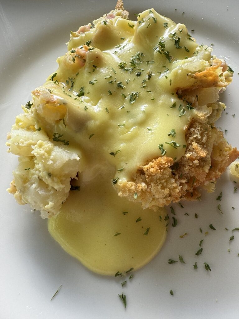 A slice of Egg Benedict Hash Brown Casserole with sauce.