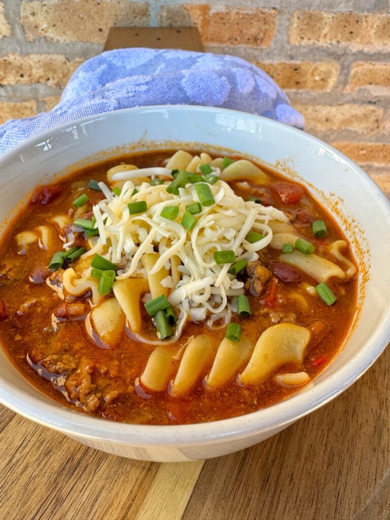 A bowl of chili mac soup with cheese on top