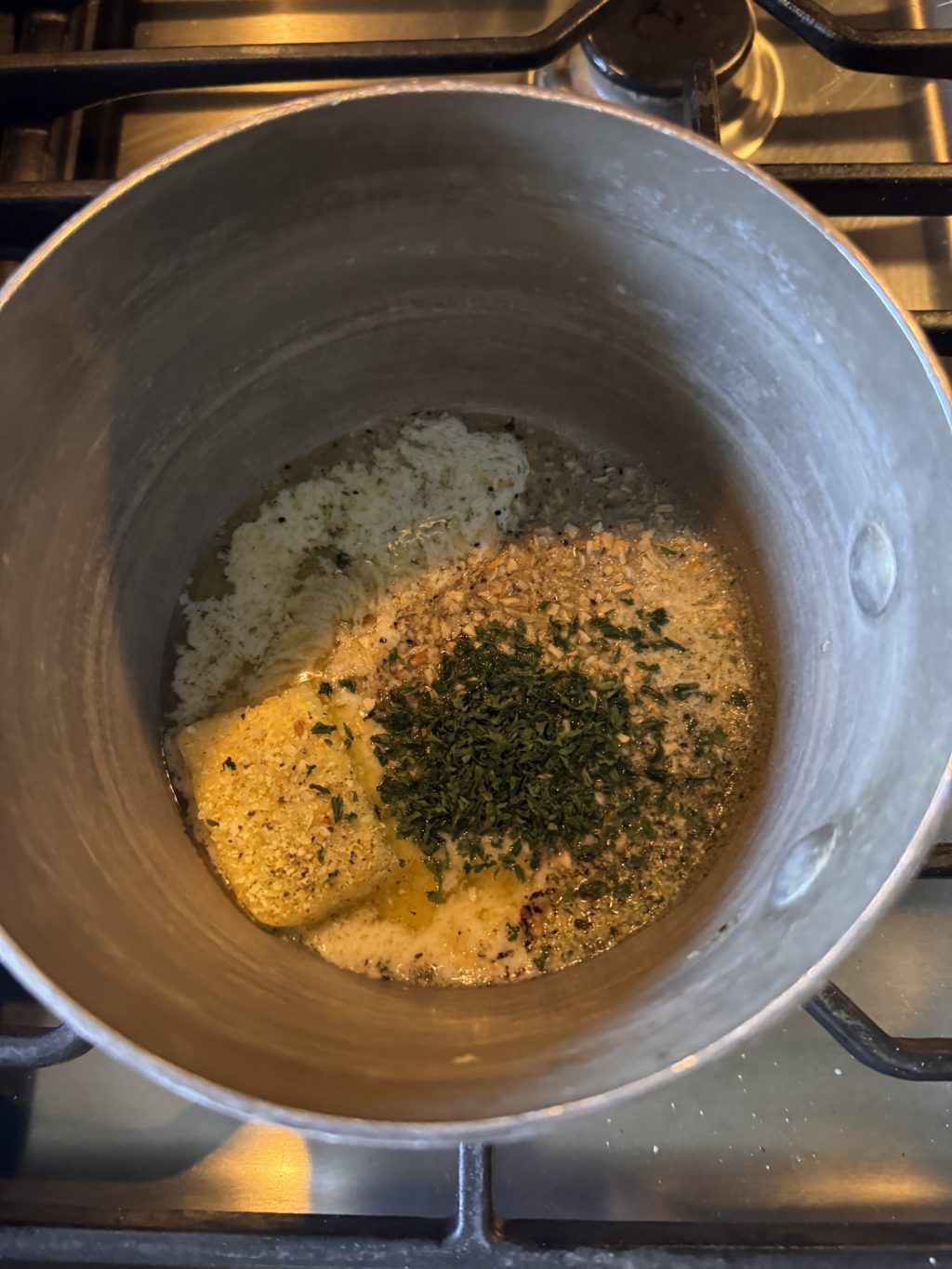 A butter and herb mixture melting up in a pot.
