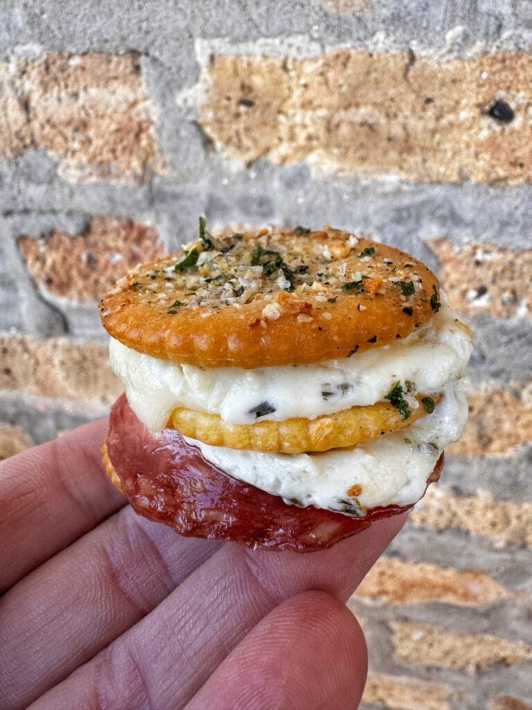 A single baked cracker snack being held on a hand.