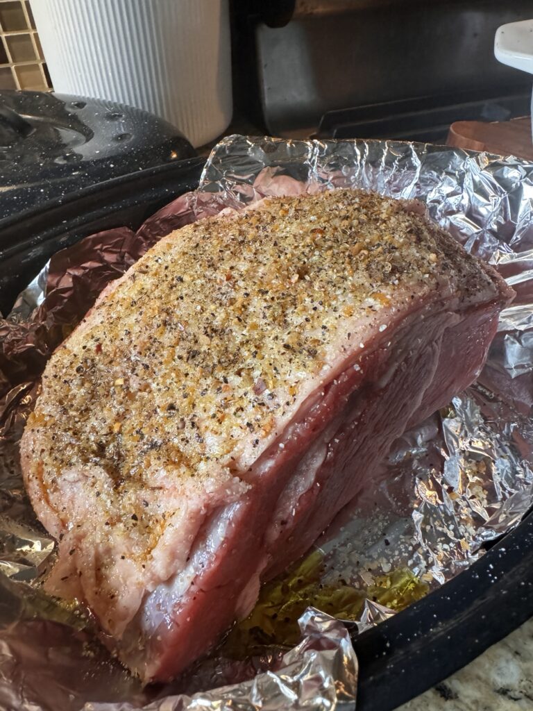 A seasoned raw beef roast on a foil covered baking pan.