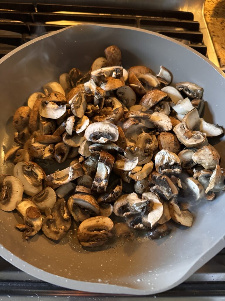 Sliced mushrooms sautÃ©ing in a pan.