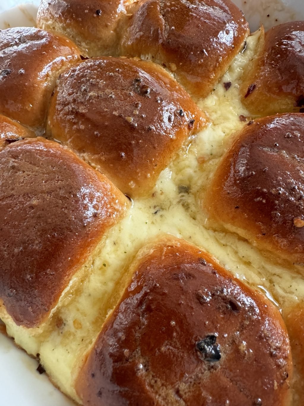 A close up of honeyed rolls with cheese oozing out in between.