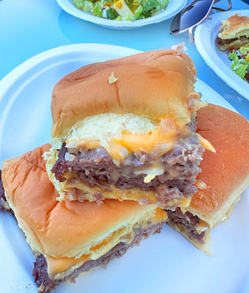 Three White Castle sliders stacked in a small pyramid on a white plate.