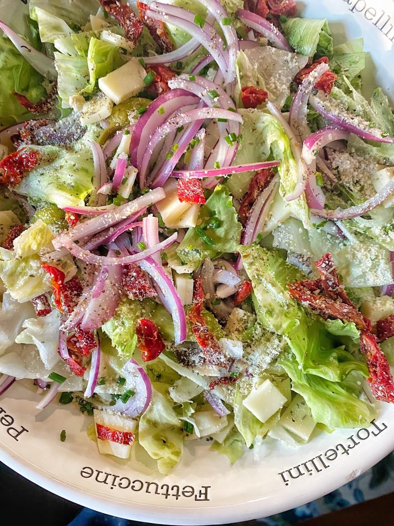 Pizza salad, consisting of lettuce, onions, cheese, and seasonings.